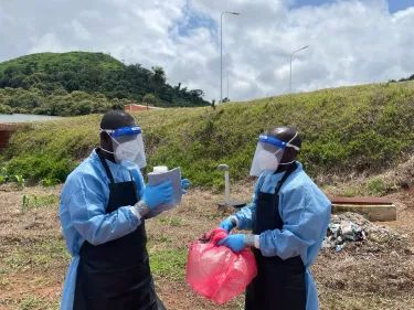two men in blue protecting gears, face shields and masks checking water