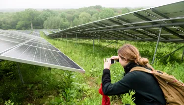 A lady pauses to take a photo during a tour of the solar panel installation on the campus of the Cummings School of Veterinary Medicine
