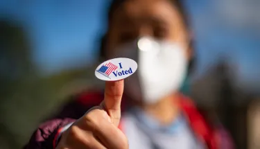 A person holds up an “I Voted” sticker on Election Day