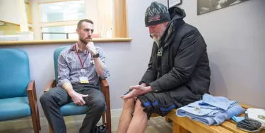 Physician and Tufts School of Medicine graduate Adam Normandin listens to a homeless man at a Portland, Maine, clinic, as the patient soaked his feet in warm water and Epsom salt to treat frostbite (Photo: Derek Davis / Portland Portland Press Herald via Getty Images)