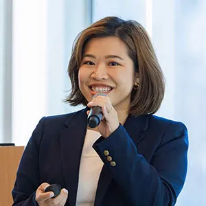 a woman in a navy blazer and white dress with a microphone