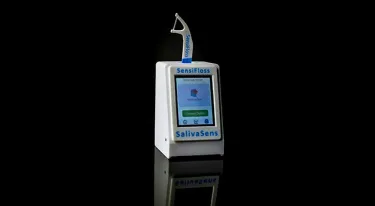 A dental floss pick sticks up out of the top of a device, with its handle inserted into the device
