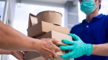 Gloved hands deliver boxes of food