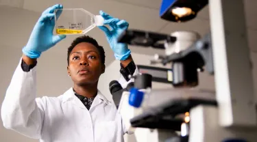 Researcher Chisaka Kuehnemann holds up a liquid for examination