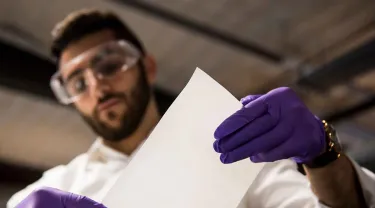 Photo of Tufts alumnus Alex Rappaport of ZwitterCo in his lab at the Greentown Labs incubator examining membranes engineered membranes to filter and treat polluted water.