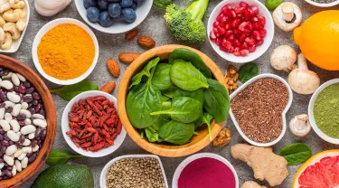 Healthy food such as dry beans, fresh spinach, green tea podwer, fruits, whole grains are on the table