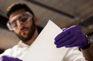 Photo of Tufts alumnus Alex Rappaport of ZwitterCo in his lab at the Greentown Labs incubator examining membranes engineered membranes to filter and treat polluted water.