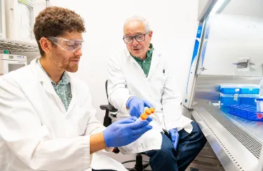 two men in lab coats examine a sample in a laboratory setting