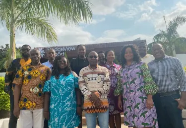 A group of people posing before an office building with palm trees to the side. Tufts researchers collaborate with two Ghanaian hospitals to break down the barriers preventing people with hypertension from getting the care they need