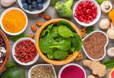 Healthy food such as dry beans, fresh spinach, green tea podwer, fruits, whole grains are on the table