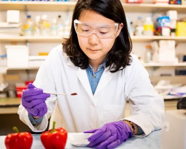  A doctoral student poses for photos with red peppers and paprika