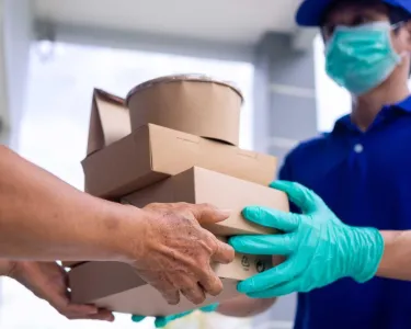 Gloved hands deliver boxes of food