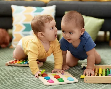 Two toddlers playing with maths toys sitting on floor at home