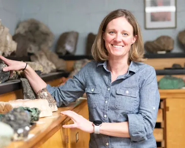 Jill VanTongeren stands with a large mineral collection on top of wooden cabinets. Rare earth elements are used in many critical industries and have become a hot political issue.